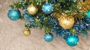 Snowing on Christmas decorated pine tree, snow falling at slow motion in winter, baubles close up video