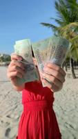 Woman counting the Vietnamese Dong on tropical beach in Vietnam video