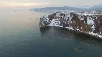 View from a drone on a snow-covered rocky seashore at sunset video