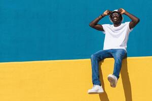 A man sitting on a wall with his hands on his head. photo