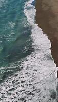aereo Visualizza cattura turchese onde ritmicamente lavaggio sabbioso costa, visualizzazione sbalorditivo oceanico paesaggio e naturale dinamico movimento video